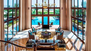Un balcón amplio con piscina, amueblado con sillas y una mesa, con vistas a un jardín exuberante.