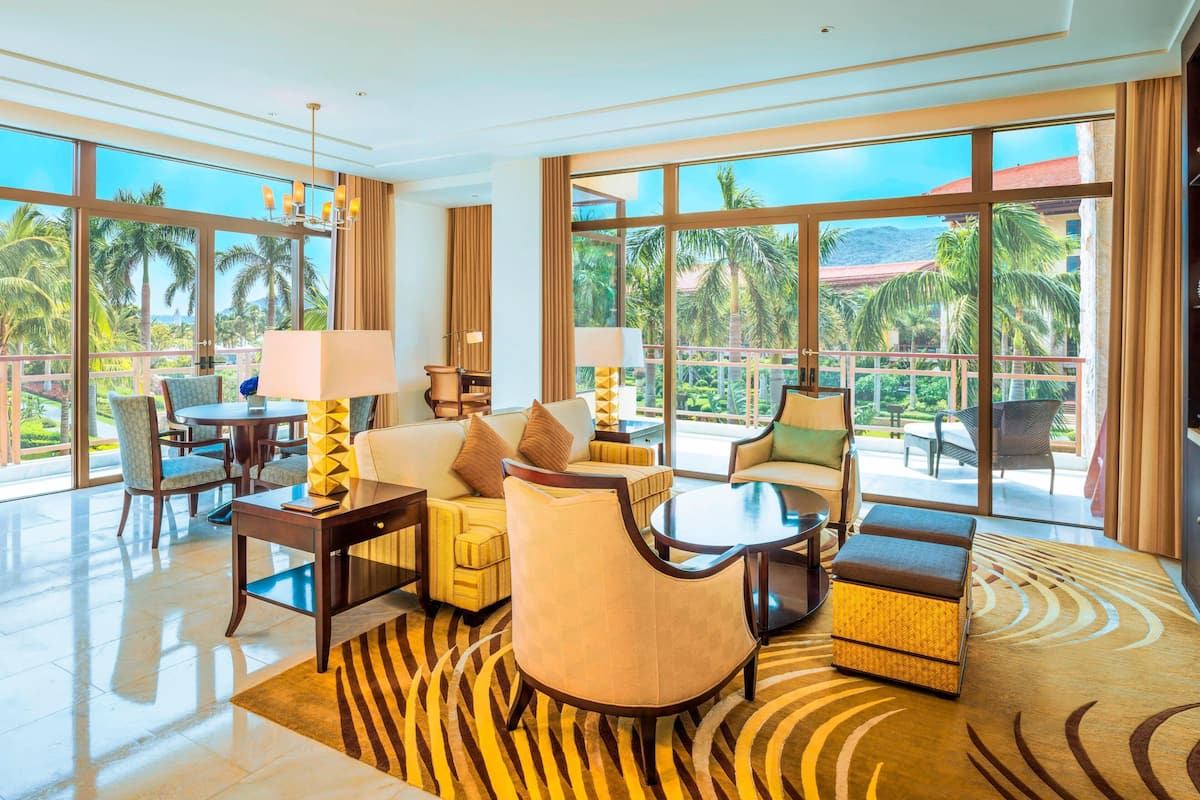 Une chambre d’hôtel spacieuse dotée d’un grand balcon, d’un ensemble de canapés, d’une table à manger et d’une table basse.