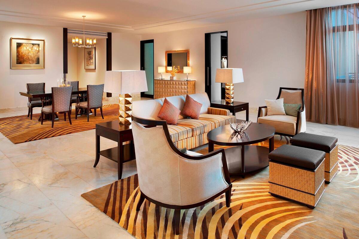Une chambre d’hôtel moderne dotée d’un coin repas, d’un ensemble de canapés et d’un grand miroir.