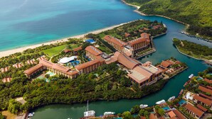 Vista aérea de un resort con varias edificaciones, una playa y un puerto deportivo.