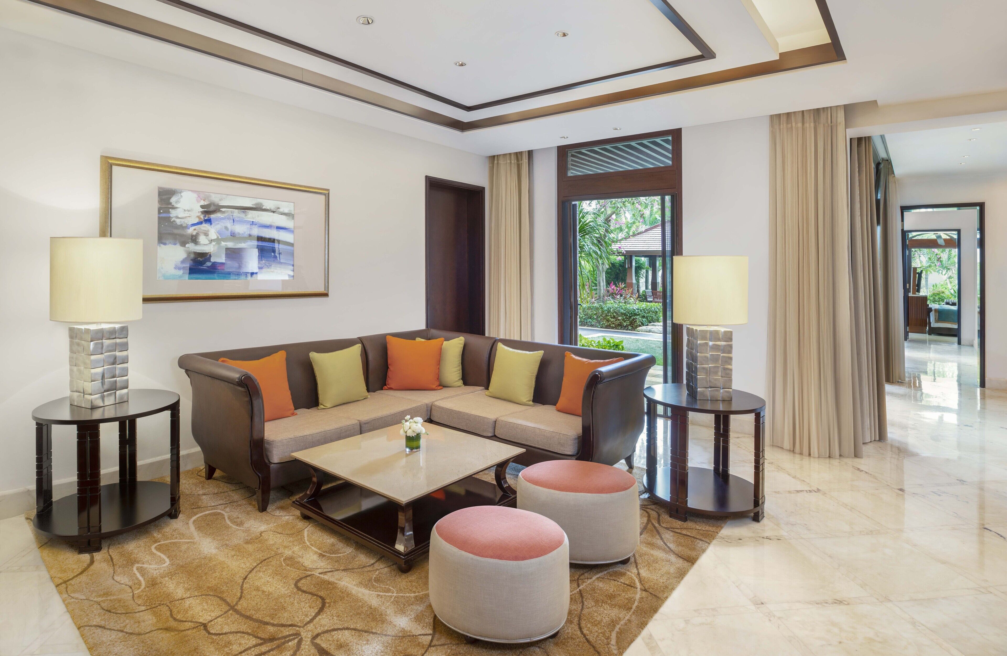 A modern living room with a sectional sofa, two round ottomans, a coffee table, and two side tables with lamps.