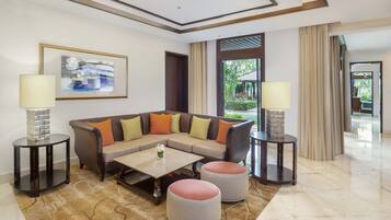 A modern living room with a sectional sofa, two round ottomans, a coffee table, and two side tables with lamps.