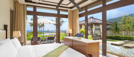 A hotel room with a large bed, a desk, and a view of the ocean.