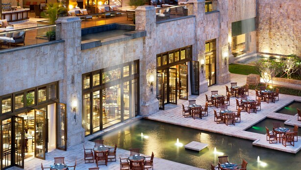 Un bar en la azotea con mesas al aire libre y una piscina.