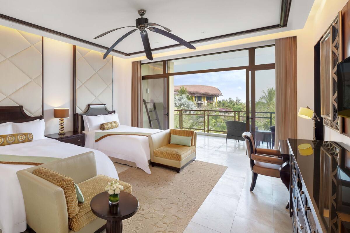 Une chambre d’hôtel avec deux lits, un balcon, un ventilateur de plafond et une télévision.