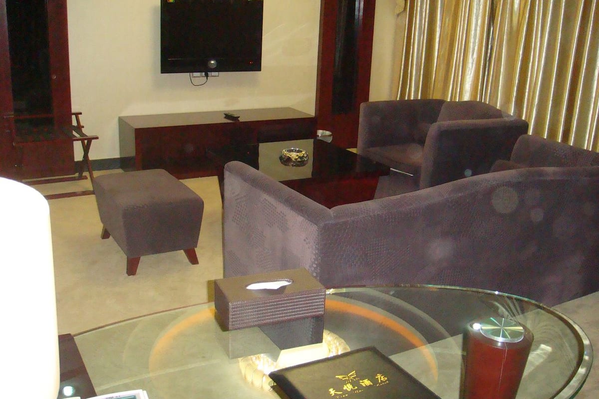 Een moderne woonkamer met een flatscreen televisie, comfortabele zitplaatsen, een glazen salontafel en een klein bijzettafeltje.
