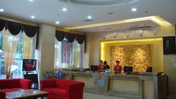 A hotel reception area with a chandelier, a reception desk, and red sofas. - Guangzhou Tianyue Hotel (Guangzhou)