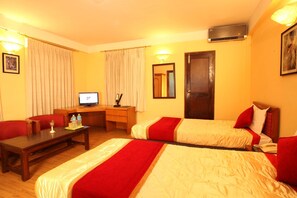 A hotel room with two beds, a desk, a television, and a mirror.