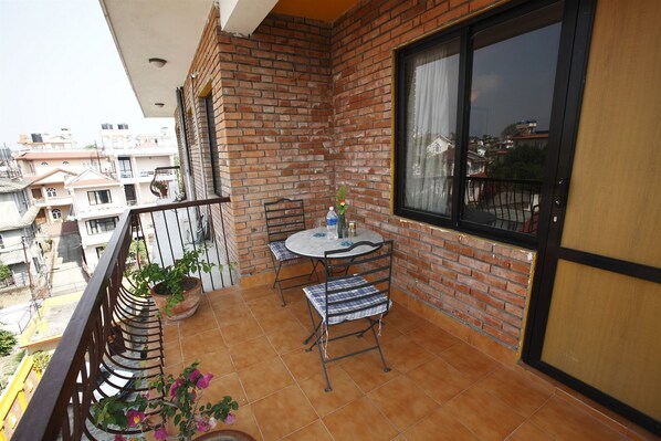 A balcony with a tiled floor, a round table with chairs, and potted plants.