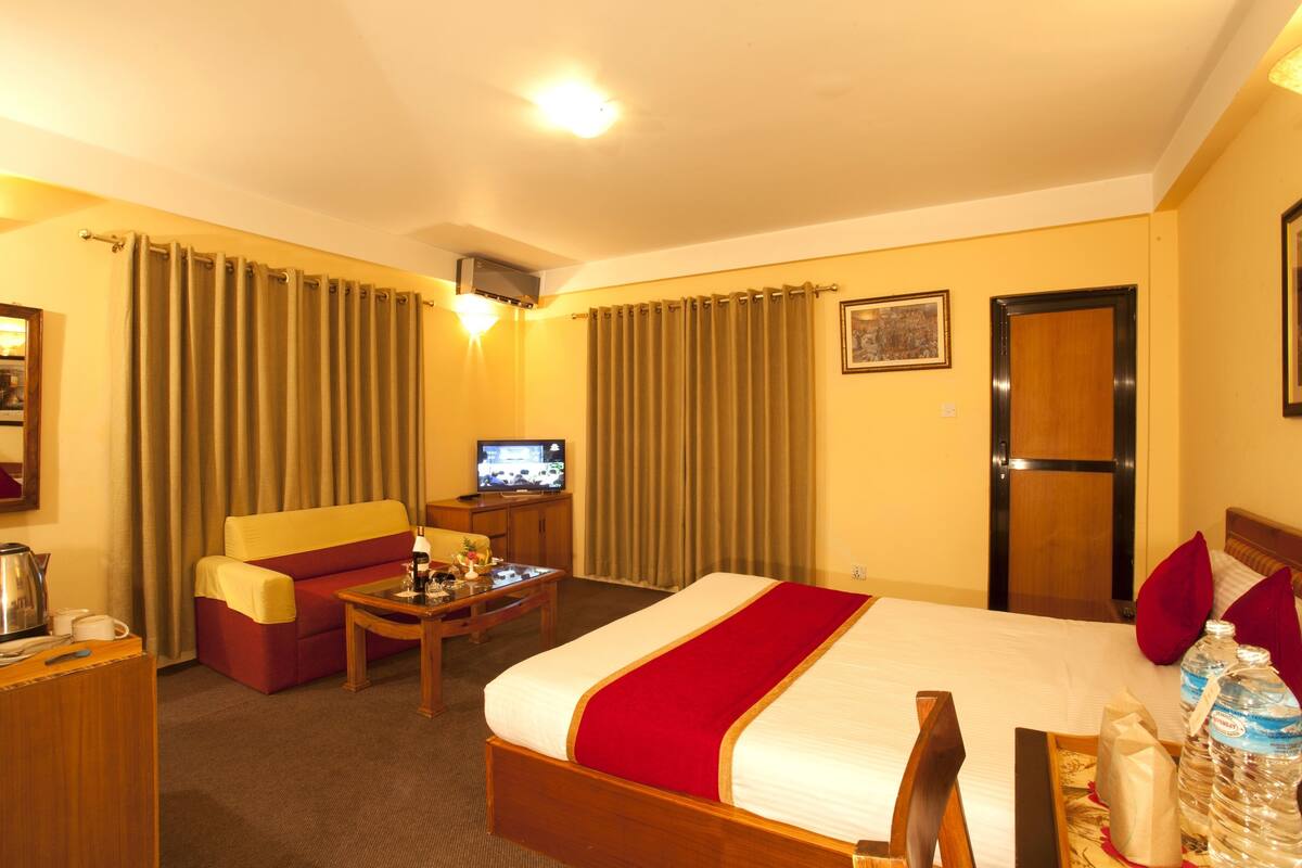 A hotel room with a bed, a sofa, a TV, and a desk.
