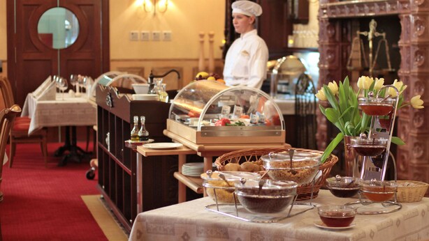 A buffet setup with various food items and a chef in the background.