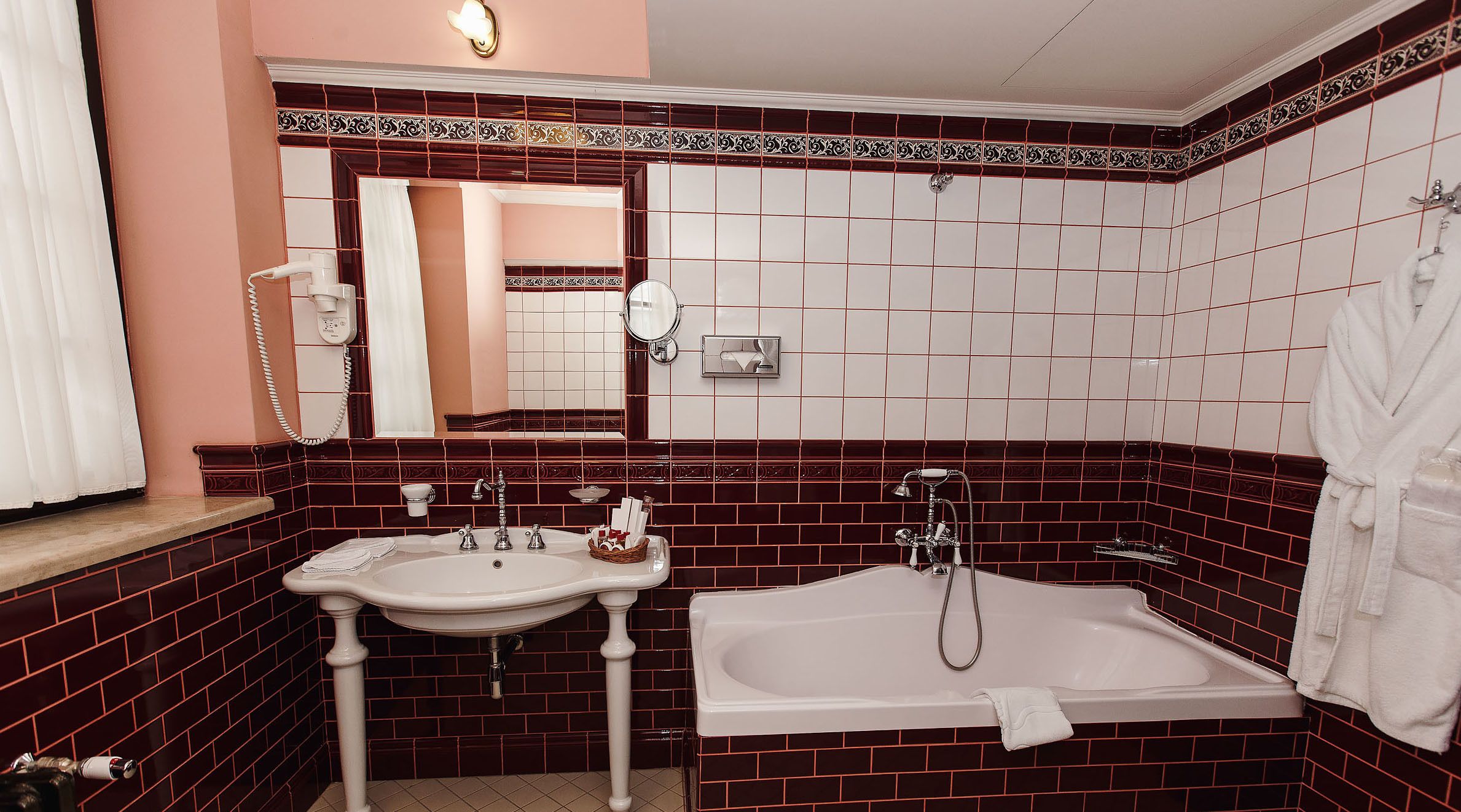 A bathroom with a white sink, a bathtub, and a mirror. There is a towel rack and a bottle of shampoo on the sink.