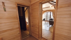 A wooden interior with a tiled floor, a doorway leading to another room, and a window with curtains.