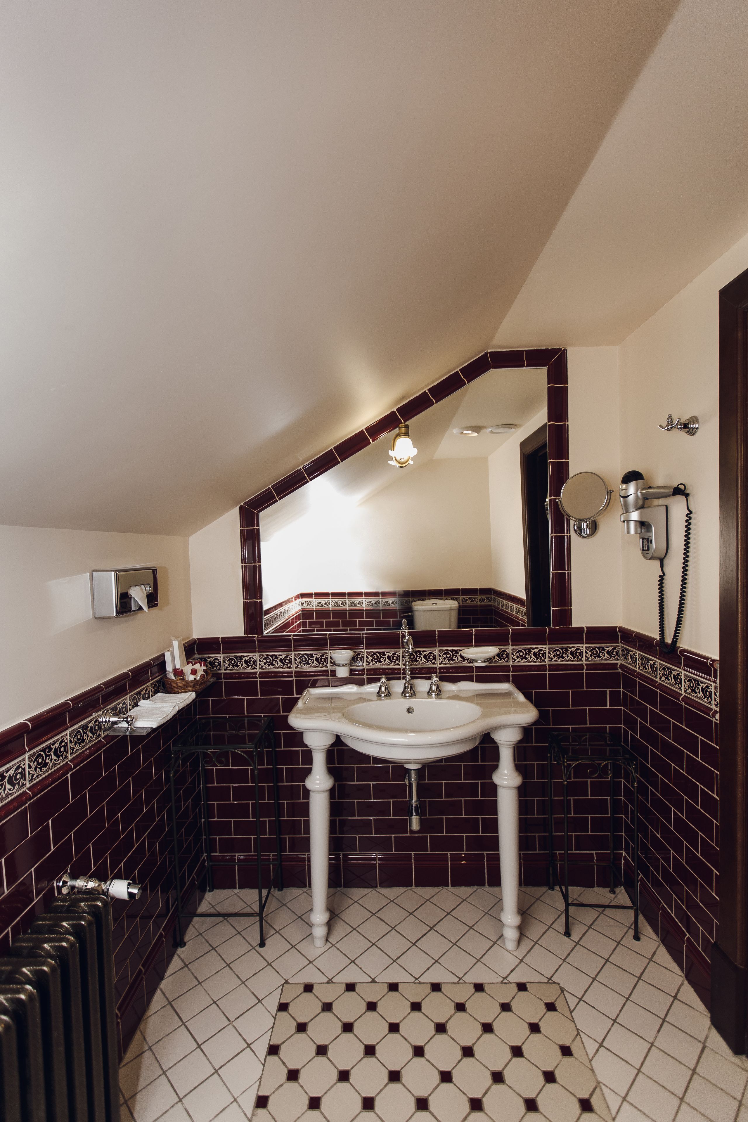 A bathroom with a white sink, dark red tiled walls, and a patterned floor.