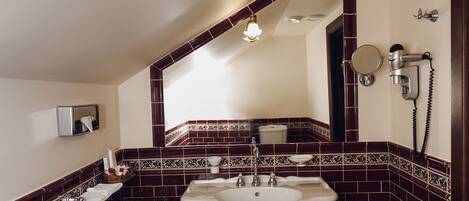 A bathroom with a white sink, dark red tiled walls, and a patterned floor.