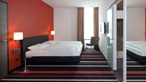 Une chambre d’hôtel avec un grand lit, un bureau, une chaise, une télévision et un espace douche.