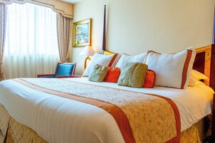 Una habitación de hotel con una cama grande, una mesita de noche, una lámpara y un cuadro en la pared.