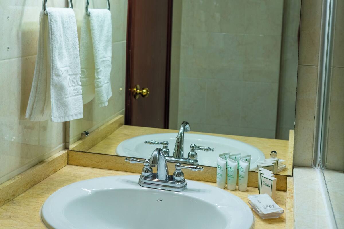 A bathroom with a sink, mirror, and towel rack.