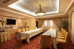 Un salón de banquetes con una larga mesa, sillas y una araña.