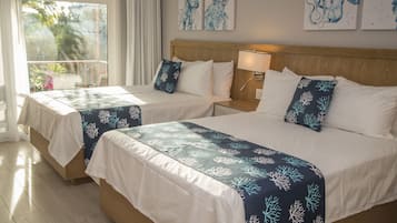 Hotellihuoneessa on kaksi sänkyä, joissa on molemmissa sinisen korallikuviollisen peitteen lisäksi valkoiset tyynyt ja puinen pääty. Huoneessa on ikkuna, jossa on verhot, yöpöytä lampun kanssa ja taideteos seinällä.