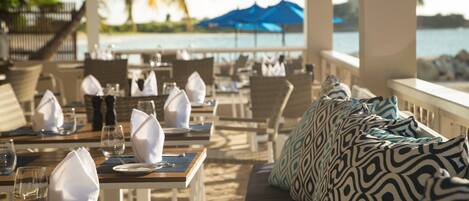 Restaurante à beira-mar com mesas preparadas para refeições, com vista para o oceano.