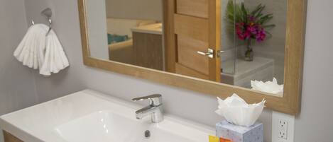 A bathroom with a white sink, a mirror, and toiletries.