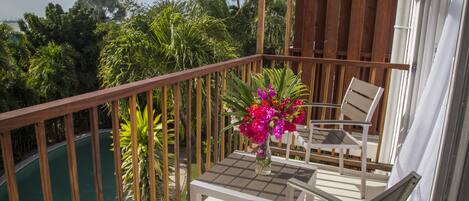 A balcony with a pool, wooden railing, and two chairs.