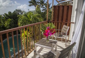 A balcony with a pool, wooden railing, and two chairs.