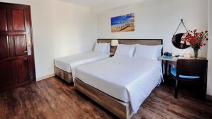 A hotel room with two beds, a wooden floor, a desk with a chair, a painting on the wall, and a door. - Golden Lotus Hotel (Nha Trang)