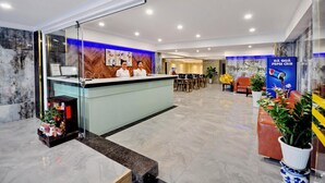 A hotel reception area with a glass partition, a reception desk, and a seating area with a sofa and chairs. - Golden Lotus Hotel (Nha Trang)