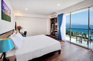 A hotel room with a large bed, a desk with a lamp, a wardrobe, and a balcony with a view of the sea. - Golden Lotus Hotel (Nha Trang)