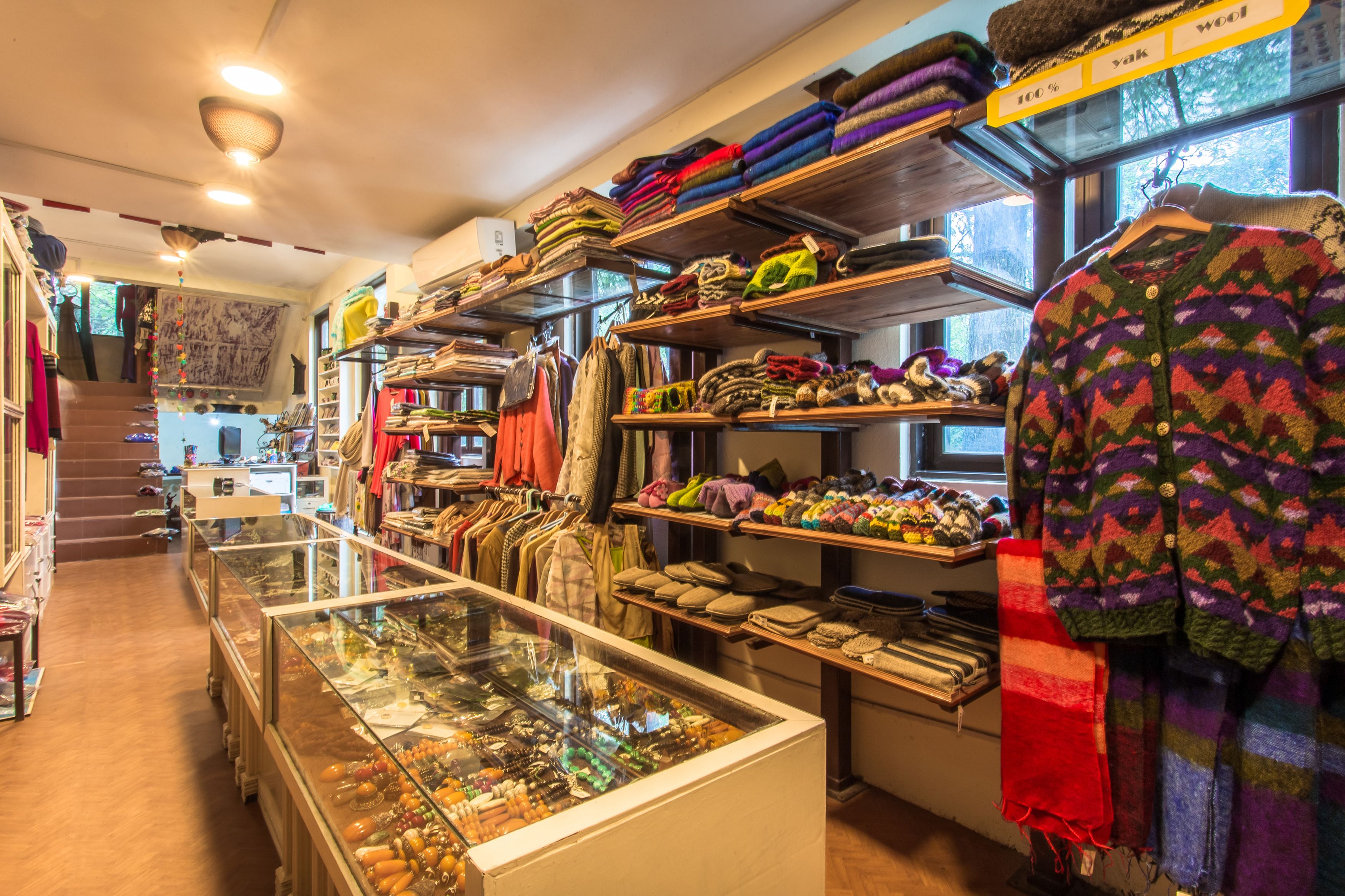 Un magasin où l’on trouve des étagères remplies de textiles aux couleurs vives et une vitrine où sont exposés des bijoux.