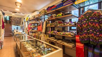 Un magasin où l’on trouve des étagères remplies de textiles aux couleurs vives et une vitrine où sont exposés des bijoux.