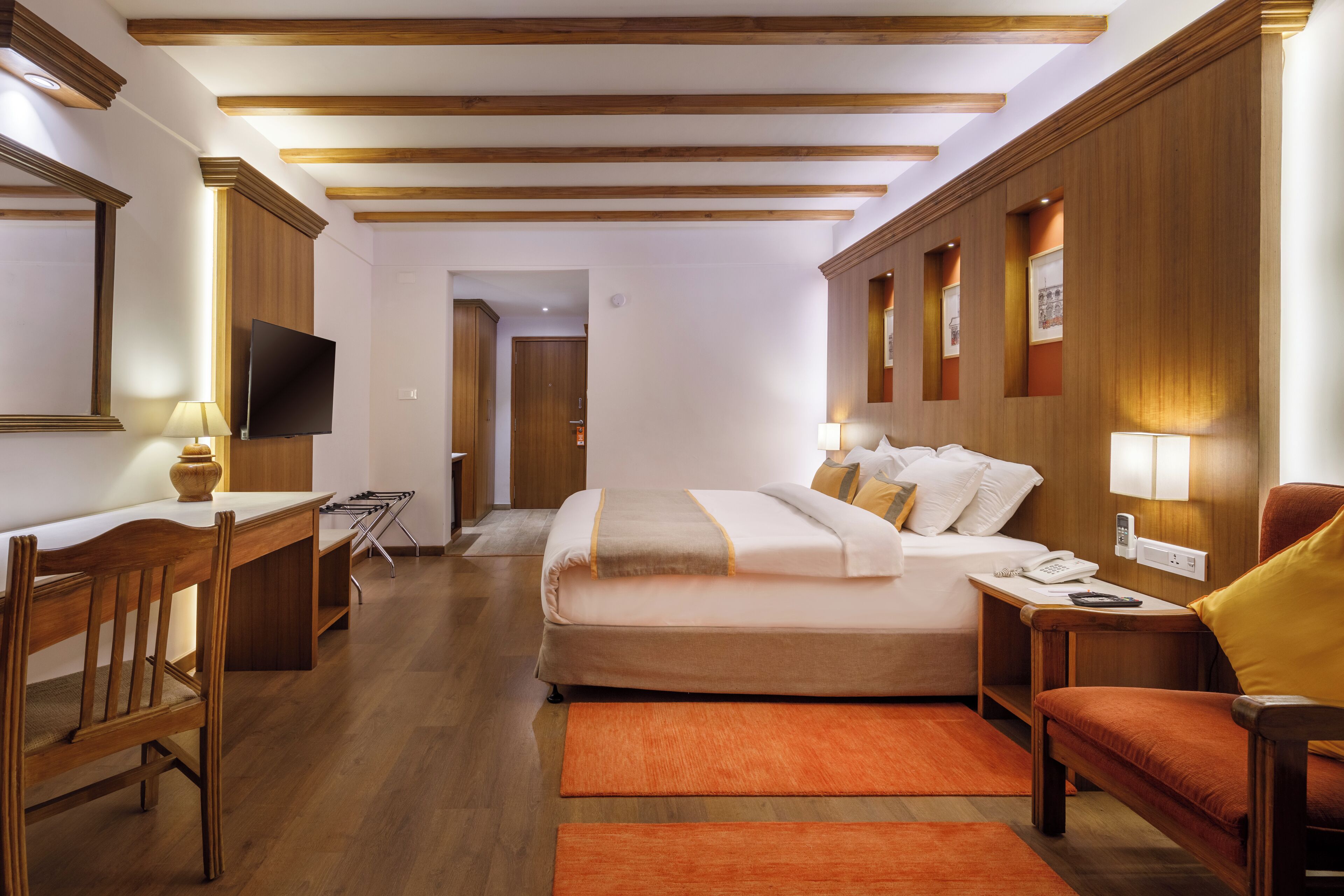 Habitación de hotel con cama, escritorio, silla y televisor.