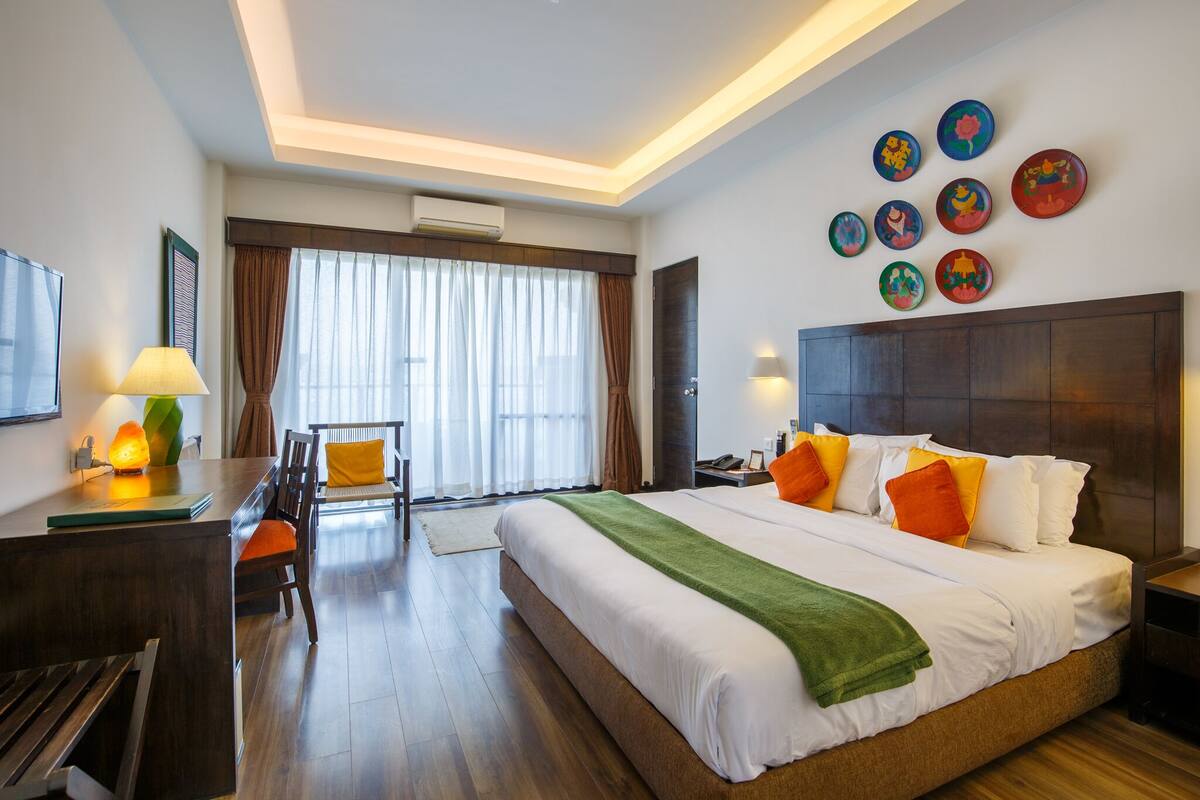 Une chambre d’hôtel avec un grand lit, un bureau, une chaise et un coin repas.