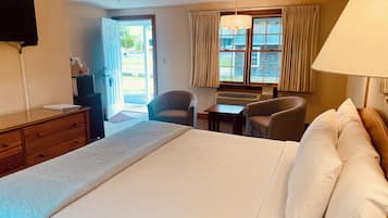 Ein Hotelzimmer mit Bett, Schreibtisch, zwei Stühlen, Fernseher und einem Fenster mit Vorhängen.