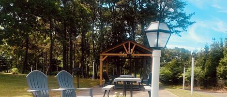 Un espacio al aire libre con sillas tipo Adirondack, mesas de picnic y un pabellón.