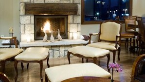 Un salón acogedor con chimenea de piedra, asientos cómodos y un amplio ventanal con vistas a la ciudad.