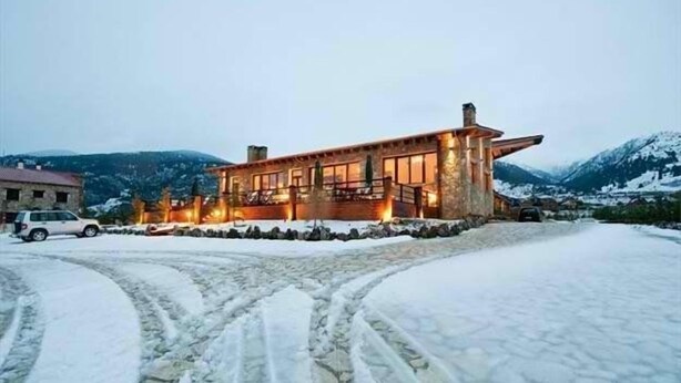 Paisaje nevado con un edificio moderno, ventanas amplias y base de piedra.