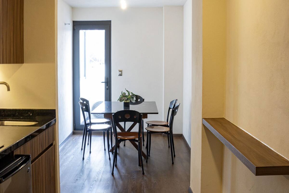 Eine moderne Küche mit Holzausstattung, ein Essbereich mit Tisch und Stühlen sowie eine Tür zu einem weiteren Raum.
