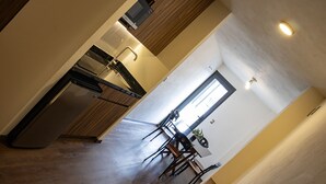 A modern kitchen with a built-in oven, a dishwasher, and a dining area with a table and chairs. - Estanza Hotel & Suites (Morelia)