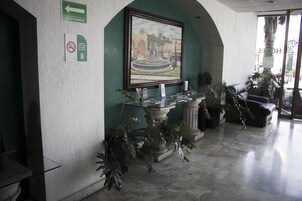 Zona de recepción con un expositor de vidrio, un cuadro enmarco y una pared verde.