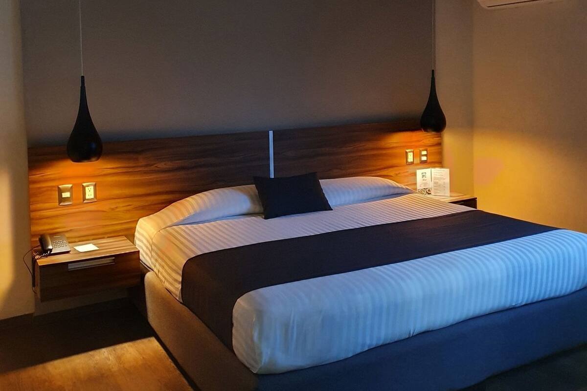 Ein Hotelzimmer mit einem großen Bett, einem Holz-Kopfschild, Nachttischen und Pendelleuchten.