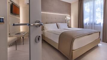 A modern hotel room with a large bed, bedside tables, a flat-screen TV, and a view of the outdoors.