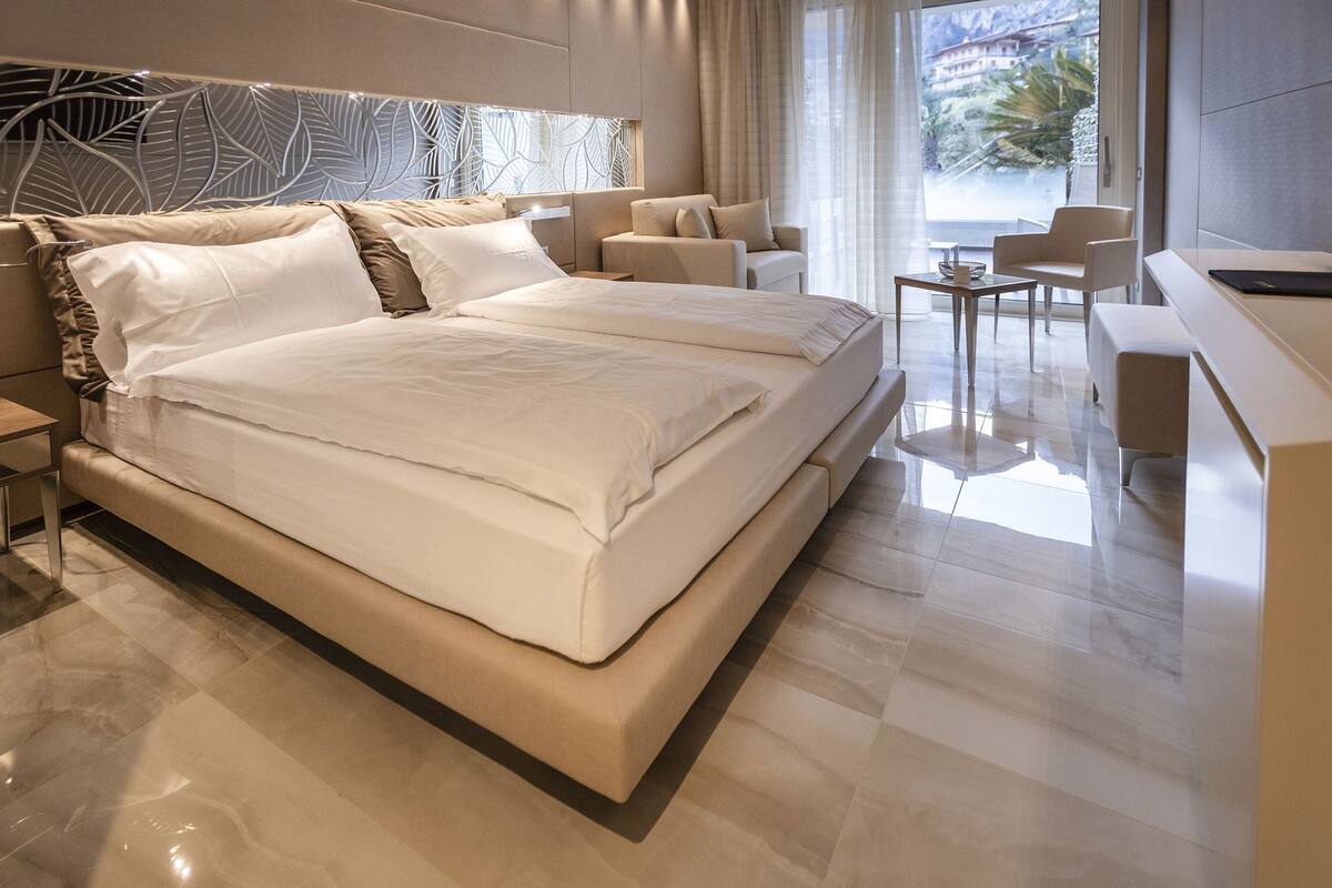 A modern hotel room with a large bed, a desk, and a view of the outdoors.