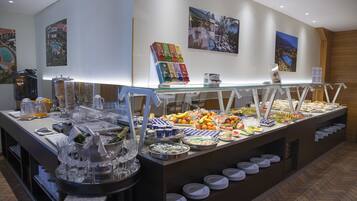 Un buffet proposant une variété d’aliments et de boissons, notamment des fruits, des fromages et un coin café.
