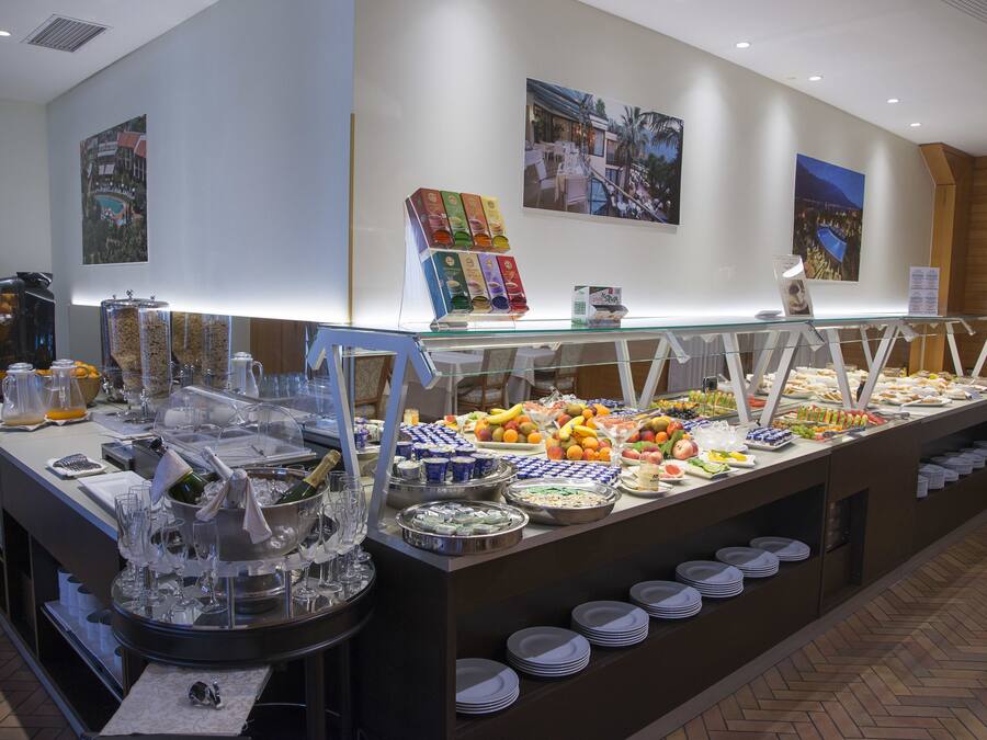 Un buffet proposant une variété d’aliments et de boissons, notamment des fruits, des fromages et un coin café.
