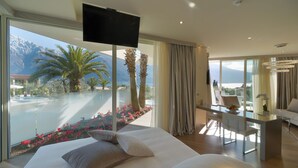 A modern hotel room with a large bed, a desk, and a view of a pool and mountains. - Park Hotel Imperial Centro Tao Natural Medical Spa (Limone sul Garda)