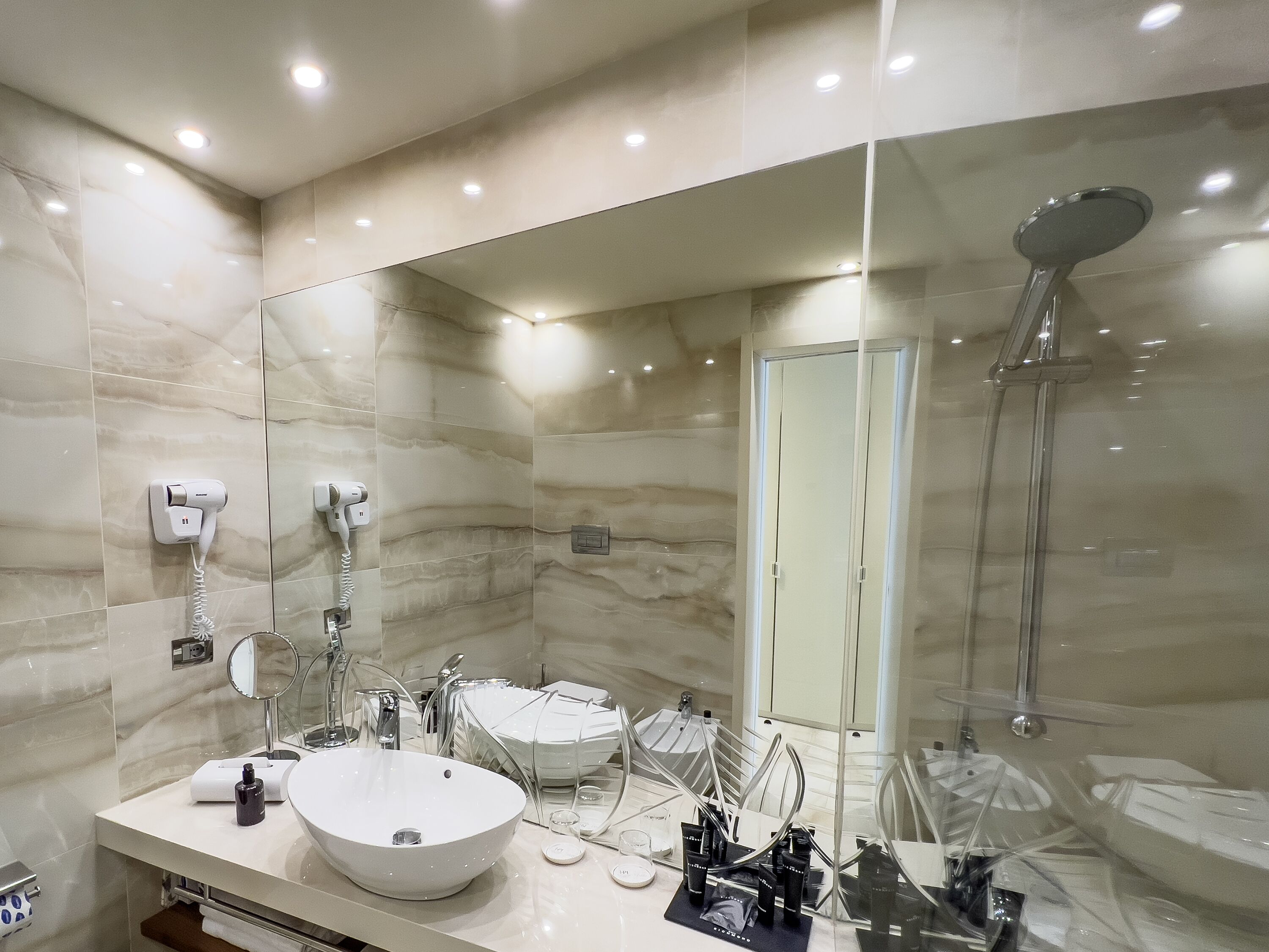 Une salle de bain moderne avec un grand miroir, un lavabo blanc et une douche.