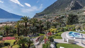 A resort with a swimming pool, palm trees, and a mountainous backdrop.